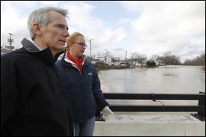 U.S. Sen. Rob Portman, left, and Findlay mayor Lydia Mihalak, right, tour the Blanchard River that reached the edge of the overpass bridge located near 104 S. Main St. in Findlay today.