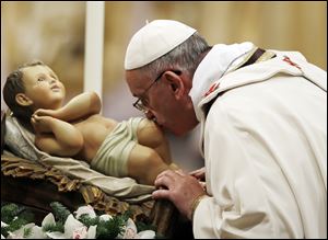 Pope Francis kisses a statue of baby Jesus as he celebrates the Christmas Eve Mass in St. Peter's Basilica at the Vatican.