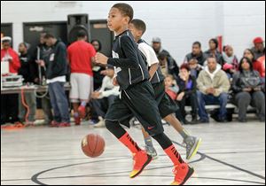 Jerry Easter III runs down the court during a basketball game at the Frederick Douglass Center. The Dunkin 4 Donations charity event exposes central-city youths to positive role models and brings toys to needy children.