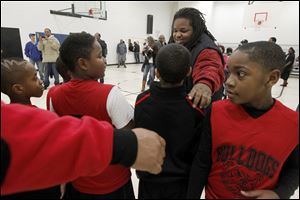 David Ross, center, one of the co-founders of Dunkin 4 Donations, organizes basketball players to take a team photo during the charity basketball event at the Frederick Douglass Center in Toledo.