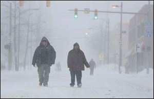 Robert Russian, left, and Joe Luna, right, make their way to Toledo-Lucas County Library's main library by walking down the middle of Madison Street.