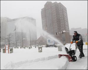 Imagination Station facility worker Robert Rising snow blows the entrance of the science center during a snow storm in downtown Toledo. Because of the heavy snowfall, Imagination Station closed for the day.