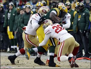 Green Bay Packers running back Eddie Lacy gets tackled by San Francisco 49ers defensive end Ray McDonald, left, and cornerback Tramaine Brock.