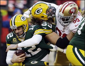 San Francisco 49ers outside linebacker Aldon Smith, right, grabs Packers quarterback Aaron Rodgers (12) as Smith fights against the Packers offensive tackle David Bakhtiari on Sunday in Green Bay, Wis.