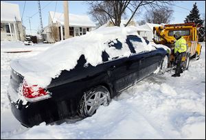 Jim Piasecki of Piasecki Service Inc. prepares to tow a car off Olson Street into the owner’s drive so city crews could plow the Toledo street. 