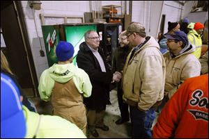 Mayor D. Michael Collins, left, shakes hands with Bob Sadowski as other employees of the Division of Streets, Bridges & Harbor surround him at its head-quarters.