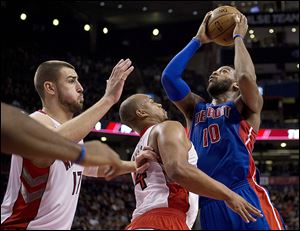 Detroit’s Greg Monroe drives against Toronto’s Jonas Valanciunas, left, and Chuck Hayes.