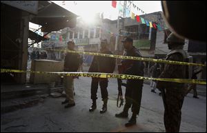 Pakistani police officers and army soldier secure a street close to the site of a suicide bombing in Rawalpindi, Pakistan today.