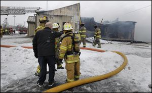 Eastwood School Board treasurer Dave Michael speaks with firefighters during a fire at the Eastwood School District administration building and bus garage today in Pemberville, Ohio.