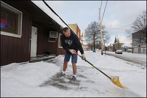 Tim Dzenis clears the snow outside his business, Tim & Ed's Bar & Grill, in his shorts, although the temperature is  about 10. Mr. Dzenis says he doesn't mind if it's 100 in the summer, and wonders whether he doesn't store all that heat to help him get through the winter.