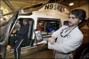 Mike Conrad of Life Flight holds a small robotic unit in the cockpit while Dr. John Whapham holds an iPad that receives images Mr. Conrad’s unit is sending to him. The technology will be used to improve care.