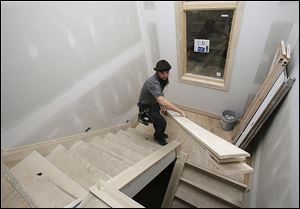 Carpenter Will Hostetler carries trim at a home under construction in Pepper Pike, Ohio. The National Association of Home Builders predicts a 30 percent increase in housing starts in 2014.