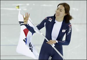 Gold medallist South Korea's Lee Sang-hwa holds her national flag and celebrates after setting a new Olympic record for the women's 500-meter speedskating at the Adler Arena Skating Center in Sochi, Russia.