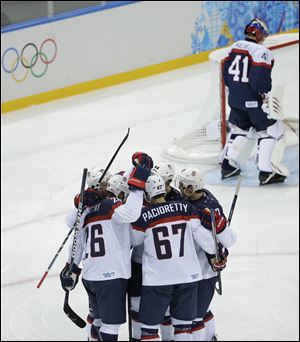 Team USA celebrates Paul Stastny's goal as Slovakia goaltender Jaroslav Halak skates in front of the net.