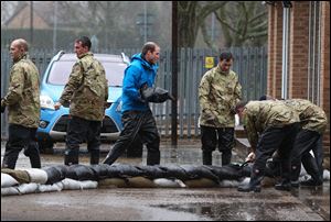 Britain's Prince William, The Duke of Cambridge, centre, unloads sandbags, with members of the armed forces,  in Datchet, England today.