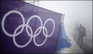 Security guards walk past the Olympic rings prior to a men's snowboard cross competition at the Rosa Khutor Extreme Park, at the 2014 Winter Olympics in Krasnaya Polyana, Russia.