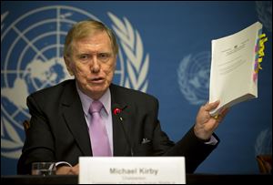 Retired Australian judge Michael Kirby, chairperson of the commission of Inquiry on Human Rights in the Democratic People's Republic of Korea, shows the commission's report during a press conference at the United Nations in Geneva, Switzerland, today.