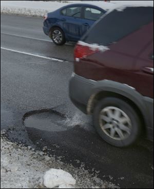 Potholes litter all three lanes of Anthony Wayne Trail in Toledo. The city says it has filled 12,664 potholes since the first of the year. In the meantime, motorists must weigh the cost of filing a claim compared to paying costs out of pocket.