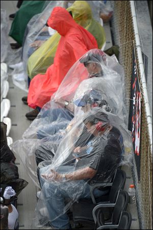 Race fans take cover from the rain in the stands on Sunday.