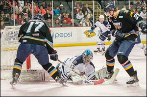 Greenville goalie Jeff Malcolm makes a stop despite the efforts of Toledo’s Kyle Rogers, left, and Maxim Shalunov. Malcolm finished with 30 saves in the win.