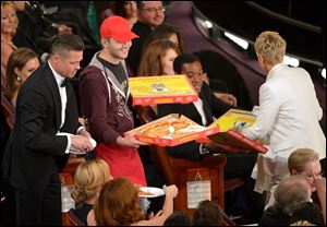 Edgar Martirosyan, center with red hat, delivers pizza to Brad Pitt, left, and Ellen DeGeneres, right, during the Oscars show on Sunday. 