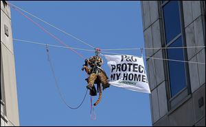 Greenpeace activists, including this one dressed in a tiger suit, rappel and hang banners in protest of Procter & Gamble outside of the company's headquarters, in downtown Cincinnati, Tuesday.