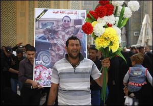 Ghaith Ismail, center, holds flowers during the funeral procession for his brother, Layth Ismail, on Thursday in the Shiite holy city of Najaf, 100 miles south of Baghdad, Iraq.