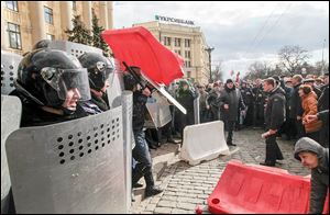 A Ukrainian riot police officer tries to shield himself from a road block thrown by pro-Russia supporters near the regional administrative building as thousands rally at a central square in Kharkiv, Ukraine.