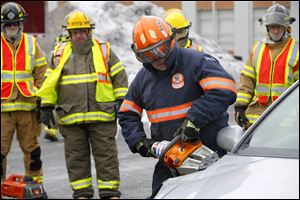 Peter Fiset, a trainer with the Northwestern Ohio Volunteer Firemen’s Association, right, shows firefighter students how to use tools to free trapped people in a Bowling Green State University lot.