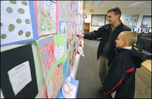 Jason Bollinger and his son Jaden Bollinger, 9, look over art.