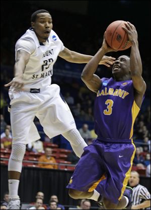 Albany guard DJ Evans (3) drives against Mount St. Mary's guard Julian Norfleet in the first half.