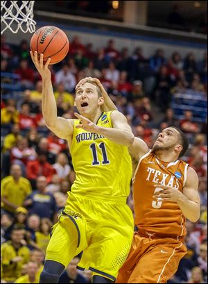 Michigan’s Nik Stauskas, who had 17 points, is fouled by Texas’ Javan Felix in an NCAA tournament game in Milwaukee. The Wolverines will play the winner of today’s Tennessee-Mercer game.