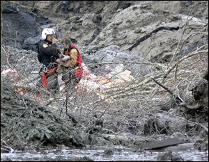 Randy Fay helps Jetty Dooper of the Netherlands a day after the mudslide. More than a week later, the search for bodies — and survivors — continues.