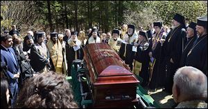 Priests gather around the casket of Metropolitan Philip Saliba at his gravesite at Antiochian Village Camp in Bolivar, Pa., before it is lowered into the ground.