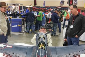 Bob Bush of Dayton, center, inspects a scale-model airplane crafted by Dave Asman of Sterling Heights, Mich., right, during the 60th annual Weak Signals Radio Control Model Exposition at the SeaGate Convention Centre in Toledo. Mr. Asman said it took him six years to build the SBD 5.