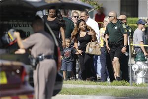 Parents with their children are escorted away with Orange County deputies after a vehicle crashed into a day care center, Wednesday in Winter Park, Fla. 