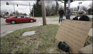 Edmond Aviv sits on a street corner holding a sign in South Euclid, Ohio declaring he's a bully, a requirement of his sentence because he was accused of harassing a neighbor and her disabled children for the past 15 years.  