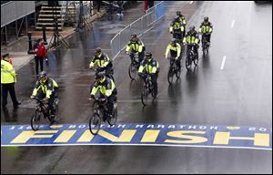 Police on bikes cycle across the Boston Marathon finish line prior to a remembrance ceremony.