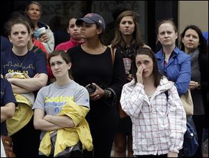 Heather McDade, of Boston, right, reacts while watching a tribute ceremony with others on an over-sized outdoor monitor.