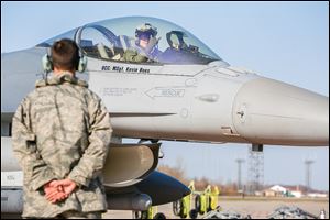 Lt. Phil Messer signals from the cockpit of his jet to a member of the ground crew during a morning exercise flight at the base in Swanton Township, which is home to a squadron of Fighting Falcons.