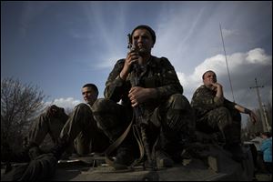 Soldiers of the Ukrainian Army sit atop combat vehicles as they are blocked by people on their way to the town of Kramatorsk on Wednesday. Pro-Russian insurgents commandeered six Ukrainian armored vehicles along with their crews and hoisted Russian flags over them Wednesday, dampening the central government's hopes of re-establishing control over restive eastern Ukraine.