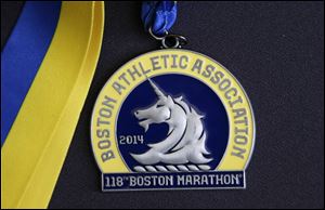 A medal for the 118th Boston Marathon is displayed in Boston. The medal is an example of those to be awarded to each finisher of the 2014 race. More than 5,000 runners were still on the Boston Marathon course when the bombs went off near the finish line in 2013. So the field was expanded for the 2014 marathon to accommodate them.