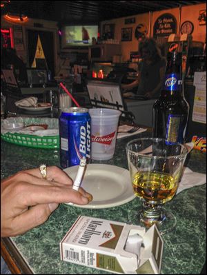 A patron smokes in a West Toledo bar despite an Oho law against lighting up.