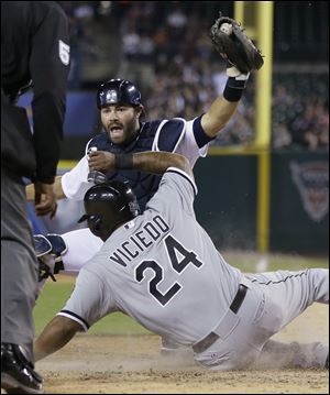 Detroit Tigers catcher Alex Avila holds up the ball to umpire CB Bucknor after tagging Chicago White Sox runner Dayan Viciedo during the seventh inning.