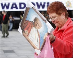 A woman places her just-purchased portrait of Pope John Paul II into a carrier bag in the pontiff’s hometown of Wadowice, Poland.