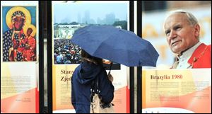 A passerby stops in front of a photo of Pope John Paul II displayed on a downtown street in Warsaw, Poland.