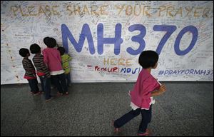 Children read messages and well wishes displayed for all involved with the missing Malaysia Airlines jetliner MH370 on the walls of the Kuala Lumpur International Airport in March.