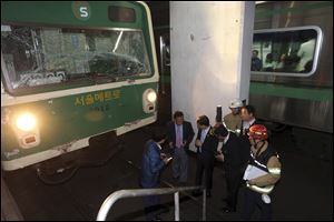 Investigators inspect the site where two subway trains collided at Sangwangshipri subway station in Seoul, South Korea, today. A subway train plowed into another train stopped at the station today, causing minor injuries for scores of people, a city official said.