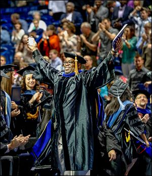 Richard Montgomery II stands and smiles widely after receiving his doctorate in educational administration. 