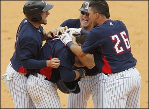 Brandon Douglas, second from left, is congratulated by Ben Guez, left, Casey Crosby, and Hernan Perez after he singled to center to plate the winning run for the Hens in the bottom of the ninth. 